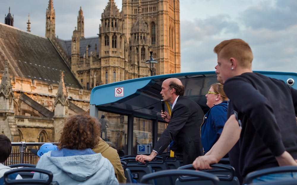 London sightseeing bus - Passengers viewing the Houses of Parliament from atop an open-top tour bus